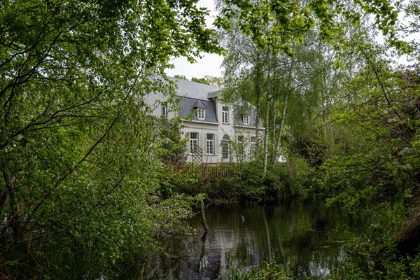 Omgracht kasteel met omliggende bossen en grote tuin, gebouwd op een motte in 1552 . Samen met het neerhof gelegen in een rechthoekige meerv...